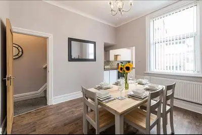 a dining room with a table and a vase of flowers at Carnarvon Stays - 2 bed Family Home - Free WiFi in Preston