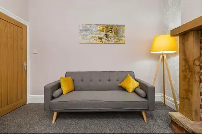 a couch with two yellow pillows in a living room at Carnarvon Stays - 2 bed Family Home - Free WiFi in Preston