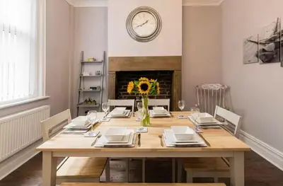 a dining room with a table and a clock on the wall at Carnarvon Stays - 2 bed Family Home - Free WiFi in Preston