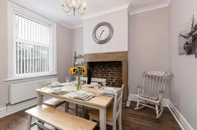 a dining room with a table and a fireplace at Carnarvon Stays - 2 bed Family Home - Free WiFi in Preston