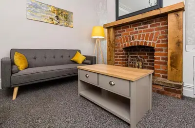 a living room with a couch and a brick fireplace at Carnarvon Stays - 2 bed Family Home - Free WiFi in Preston