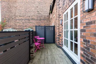 a balcony with two pink chairs and a brick building at 3BR Georgian Quarter Coach Houses - Private Parking in Liverpool