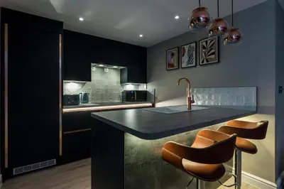a kitchen with black cabinets and a counter with stools at 3BR Georgian Quarter Coach Houses - Private Parking in Liverpool