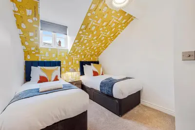 a bedroom with two beds and a yellow wall at 3BR Georgian Quarter Coach Houses - Private Parking in Liverpool