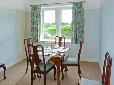 a dining room with a table and chairs and a window at Priory View in Ulverston