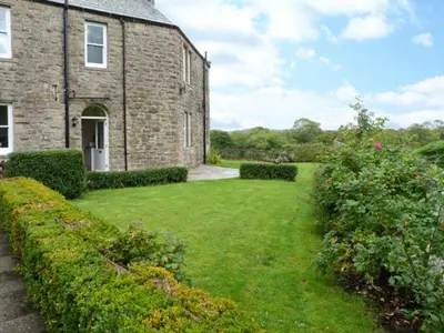 a brick house with a grass yard in front of it at Priory View in Ulverston
