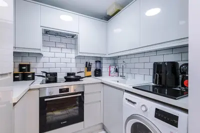 a kitchen with white cabinets and a washer and dryer at Long Stays Offers , New 2 Bed APT , Sleeps 3 , Wigan , Perfect for Relocations , Contractors , Families in Ince-in-Makerfield
