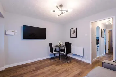 a living room with a table and a tv on the wall at Long Stays Offers , New 2 Bed APT , Sleeps 3 , Wigan , Perfect for Relocations , Contractors , Families in Ince-in-Makerfield