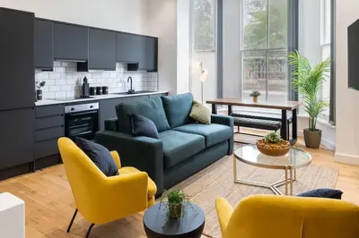 a living room with a blue couch and yellow chairs at Cozy 2 Beds Apt, Sleeps 8 with FREE parking in Liverpool