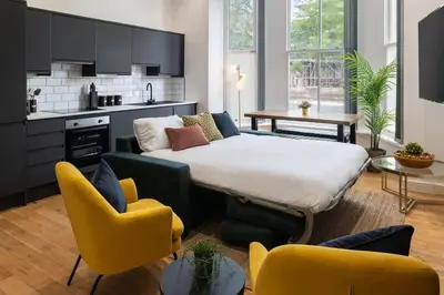 a living room with a bed and two yellow chairs at Cozy 2 Beds Apt, Sleeps 8 with FREE parking in Liverpool