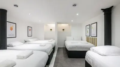 a row of beds in a room with white walls at The Bloc - Liverpool Nightlife Apartments in Liverpool