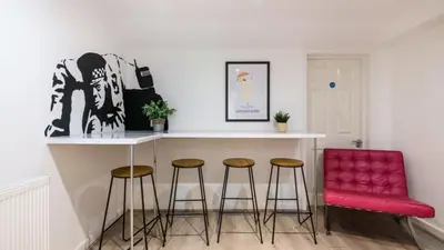 a kitchen with a bar with stools and a red chair at The Bloc - Liverpool Nightlife Apartments in Liverpool