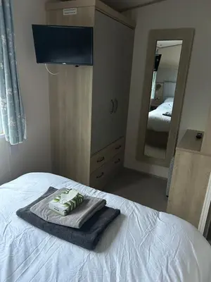 a bedroom with a bed with a towel and a mirror at Haven Cala gran in 2026 through to Jan 2027 spring summer winter breaks Blackpool Fleetwood entire home 6 people seaside holiday park in Fleetwood