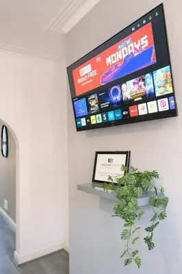 a television on a wall in a room with a plant at Whitland House by Serviced Living Liverpool in Liverpool