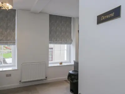 a room with two windows with grey roman blinds at Derwent in Ulverston