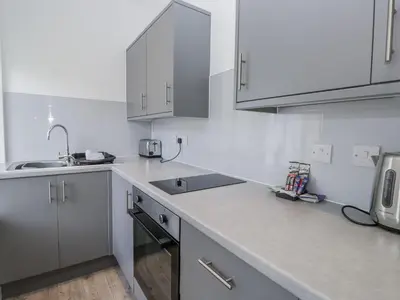 a white kitchen with white cabinets and a sink at Derwent in Ulverston
