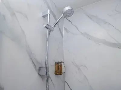 a shower in a bathroom with white marble walls at Derwent in Ulverston