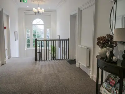 a hallway with white walls and a staircase with a window at Derwent in Ulverston