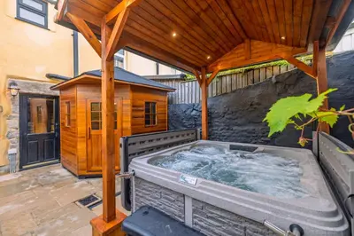 a hot tub on a patio with a wooden roof at Spa Cottage - Hot Tub, Cold Pod & Sauna in Morecambe