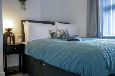 a bed with a blue comforter and pillows on it at Modern 3-Bedroom Home - Contractor Friendly - Sleeps 5 - FAST WiFi - Parking in Seacombe