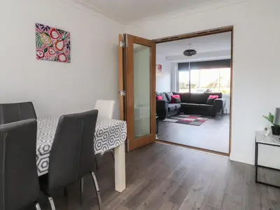 a dining room with a table and a living room at Beach Side Bungalow in Lytham St Annes