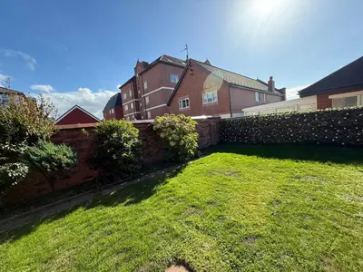 a backyard with a brick fence and a grass yard at Beach Side Bungalow in Lytham St Annes