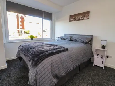 a bedroom with a bed and a large window at Beach Side Bungalow in Lytham St Annes