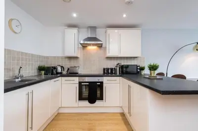 a kitchen with white cabinets and a black counter top at Central 2 Bed Apt with Balcony in Liverpool