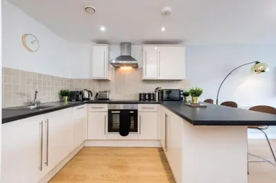 a kitchen with white cabinets and a black counter top at Central 2 Bed Apt with Balcony in Liverpool