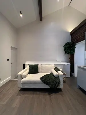 a living room with a white couch with a green blanket at Liverpool Willow House - 4 Bed Close to Anfield Stadium in Liverpool