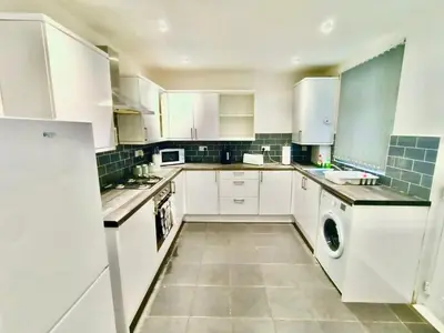 a kitchen with white cabinets and a washer and dryer at Cosy 4 Bedroom Liverpool Contractor & Family Stay in Liverpool