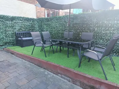 a table and chairs with an umbrella on grass at Cosy 4 Bedroom Liverpool Contractor & Family Stay in Liverpool