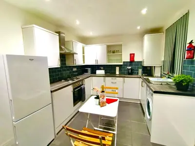 a kitchen with white appliances and a table and chairs at Cosy 4 Bedroom Liverpool Contractor & Family Stay in Liverpool