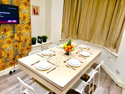 a dining room with a table with chairs and a television at Cosy 4 Bedroom Liverpool Contractor & Family Stay in Liverpool