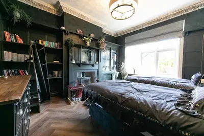 a bedroom with two beds and a window and bookshelves at Crookdale House By Holiday Heim Country Manor With Private Pool And Bar in Preesall