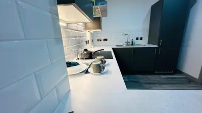 a kitchen with black cabinets and a white counter top at Preston City centre Winckley Square Flat in Preston