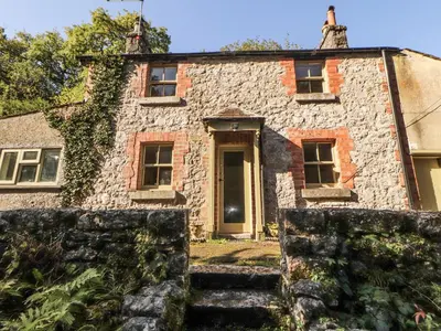 an old stone house with a stone staircase in front of it at Rock Cottage in Milnthorpe