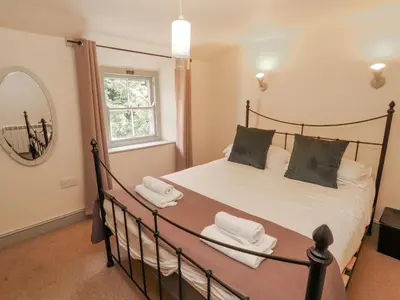 a bedroom with a bed and a mirror at Rock Cottage in Milnthorpe