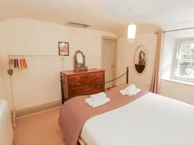 a bedroom with a bed and a dresser and a mirror at Rock Cottage in Milnthorpe