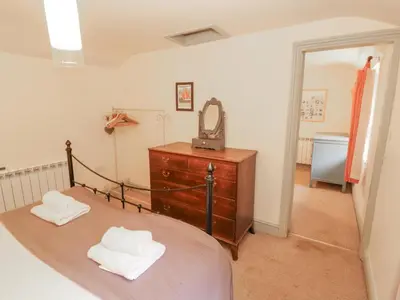 a bedroom with a bed and a dresser and a mirror at Rock Cottage in Milnthorpe