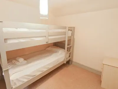 a bunk room with white bunk beds in it at Rock Cottage in Milnthorpe