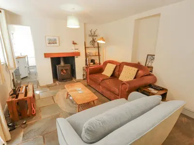 a living room with a couch and a fireplace at Rock Cottage in Milnthorpe