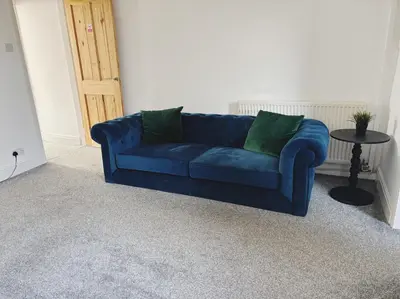 a blue couch with green pillows in a living room at Wordsworth House by Sapphire Properties -Near to BAE Systems in Barrow in Furness