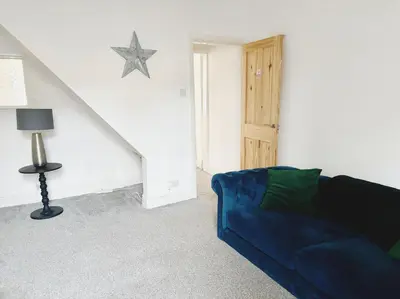 a living room with a blue couch and a staircase at Wordsworth House by Sapphire Properties -Near to BAE Systems in Barrow in Furness