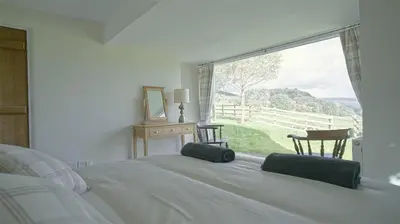 a bedroom with a bed and a large window at Tunstall Ing Farmhouse - Duchy of Lancaster Estate in Whitewell