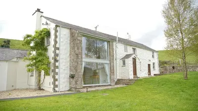 a white brick house with a large window at Tunstall Ing Farmhouse - Duchy of Lancaster Estate in Whitewell