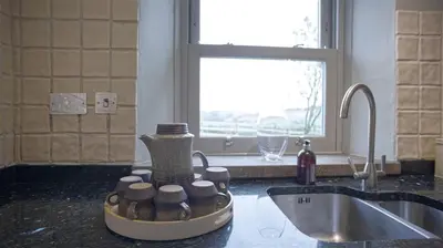 a kitchen counter with a sink with cups on it at Tunstall Ing Farmhouse - Duchy of Lancaster Estate in Whitewell