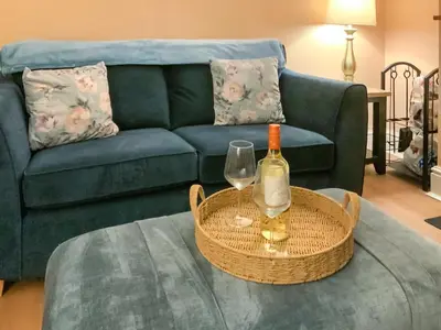 a living room with a couch and a table with a bottle of wine at Paddy's Cottage in Flookburgh