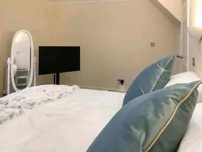 a bedroom with a bed with a mirror and a tv at Paddy's Cottage in Flookburgh