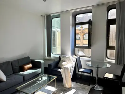a living room with a couch and a table and windows at 65 Inch TV City Center 1BR Long Stay Ready in Liverpool
